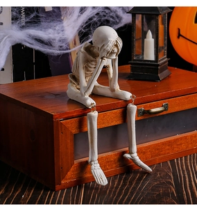 Close-up of resin skeleton figurine sitting with hands over face for Halloween decor