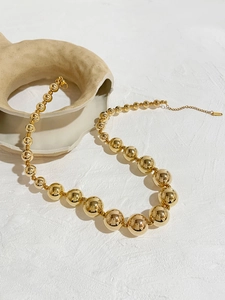 Macro shot of 18K gold bead necklace with gradient balls on a ceramic vase