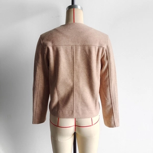 Detail view of the back of a casual cropped tweed jacket in light brown on a mannequin