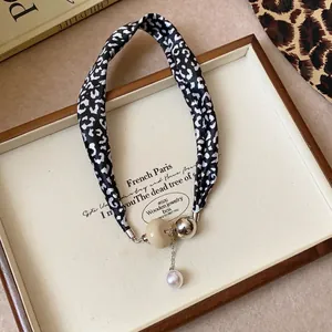 Collier ethnique avec tissu imprimé léopard et perles mixtes sur un plateau en bois