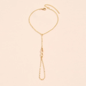 Detail view of a gold infinity charm anklet with adjustable chain on a pink background