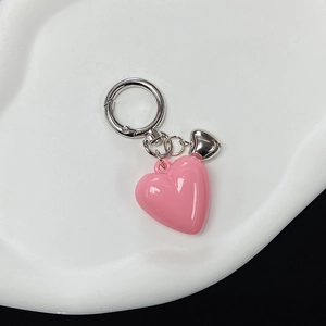 Detail of creative pink resin heart keychain with silver metal clasp on white tray