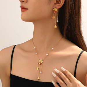 Detail view of ladybug and daisy jewelry set featuring red enamel and white pearls