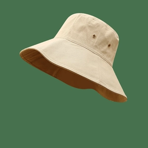 Detail of a beige wide-brim sun hat with canvas texture and metal ventilation eyelets