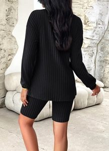 Rear view of women's black ribbed knit lounge set featuring long sleeve top and biker shorts
