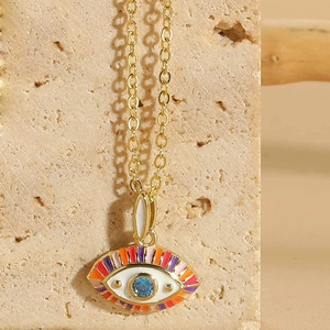 Macro view of evil eye necklace pendant with colorful enamel and blue crystal detail