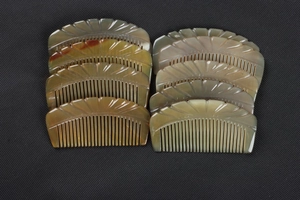 Detailed view of ten stacked semi-circular yak horn combs with natural texture and carvings