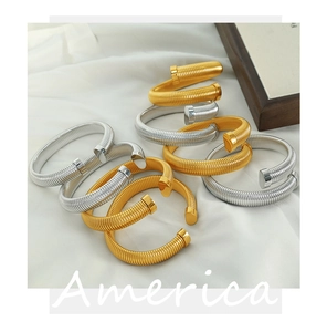 Detailed macro view of spiral spring cuff bracelets in polished gold and silver finishes
