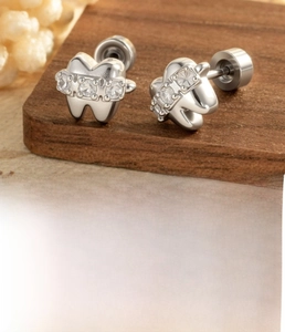 Macro detail of tooth-shaped stud earrings in silver steel with sparkling zircon inlay