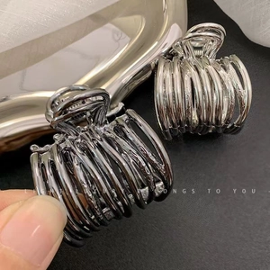 Detailed macro view of hollow metal hair claws in silver and gunmetal finishes