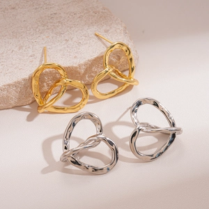 Twisted hollow heart stud earrings in gold and silver plating on stone background