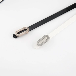 Detail of black and white skinny belts featuring sparkling rhinestone-studded oval buckles
