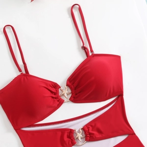 Detail van rode bikini met gouden zeester metalen ringen en cutout ontwerp op wit oppervlak