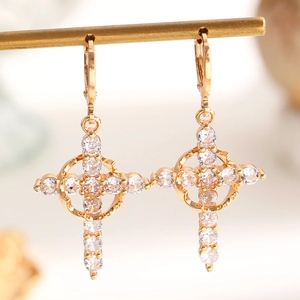 Macro shot of gold-plated cross earrings with shimmering white cubic zirconia stones