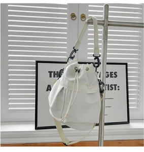 Detailed view of a white nylon bucket bag with drawstring closure and adjustable strap