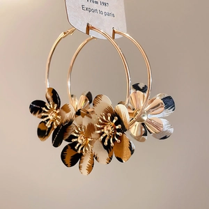 Close-up of golden hoop earrings featuring leopard print fabric flowers and stamen details