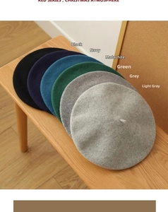 Stack of wool berets in black, navy, and green colors displayed on a wooden bench