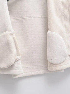 Close-up of plush white shearling vest showing thick texture and pocket stitching detail