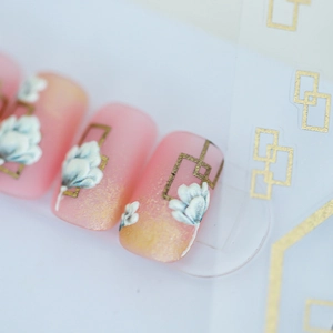 Pink and gold gradient nail stickers with white embossed floral patterns and gold lines