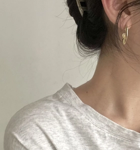 Close-up of a model wearing a minimalist golden U-shaped hoop earring on a clean background