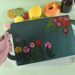 Detail of dark green resin tray with embedded dried flowers and wide side handles
