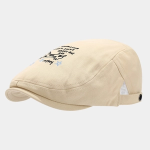 Close-up of beige cotton beret featuring cartoon dog embroidery and Happy Day text
