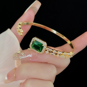 Detail of emerald green gemstone cuff bracelet with cubic zirconia on gold-plated metal