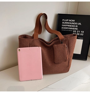 Close-up of brown woven tote bag with matching zippered pouch and wide fabric strap