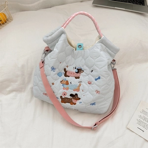 Close-up of light blue quilted tote with cute dachshund embroidery and pink handles