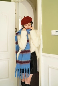 Close-up of thick blue striped scarf with burgundy fringe and soft plush texture