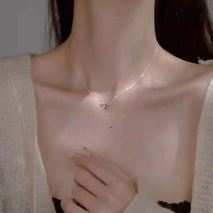 Silver double ring pendant necklace with ball tassel fringe on female model neck