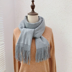 Detailed view of gray cashmere-like scarf with soft fringe on a mannequin