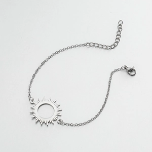 Silver stainless steel chain bracelet with a sunburst pendant and lobster clasp on light grey