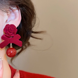 Gros plan de boucles d'oreilles rose et nœud floqués rouges portées par un mannequin