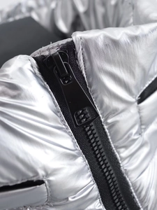 Détail macro de la fermeture éclair noire sur la veste matelassée argentée métallisée