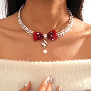 Detail of double-layer necklace with red bow, snowflake pendant and faux pearls