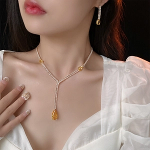 Detailed view of model wearing a sparkling yellow zircon teardrop necklace and earring set