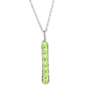 Detail of silver chain with seven green spotted beads in a wire-wrapped U-shape pendant