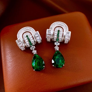 Macro detail of silver drop earrings featuring emerald green stones and zircon inlay