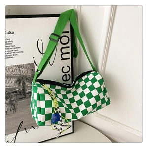 Close-up of green checkerboard canvas cylinder bag with yellow cord and blue tag