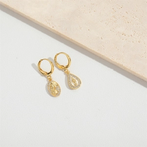 Detailed close-up of golden drop earrings with religious reliefs and micro-set crystals