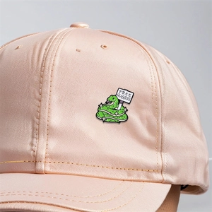Cartoon snake enamel pin with Free Hugsss text pinned on a pink satin baseball cap