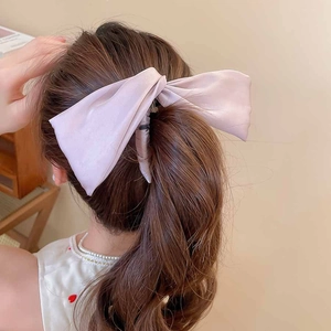 Détail de la barrette à cheveux rose en tissu portée sur une queue de cheval