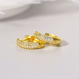 Macro shot of gold-plated hoop earrings featuring three rows of sparkling zircon stones