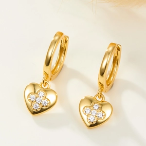 Close-up of golden heart earrings with sparkling zircon four-leaf clover inlay detail