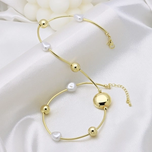 Elegant gold bead bracelet with white heart charms on white satin background