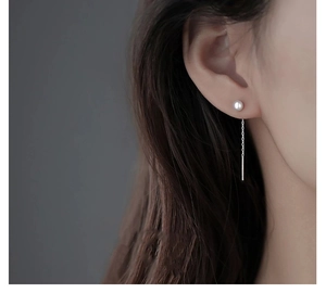Gros plan de boucles d'oreilles traversantes en argent S925 avec perle et long gland