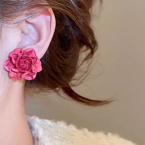 Close-up of elegant rose flower stud earrings in deep pink on a model's ear