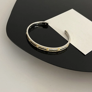 Detail of 18K gold-plated star charms with crystals on a textured two-tone open bangle
