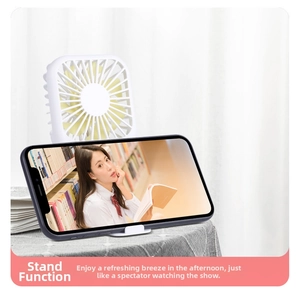 Close-up of portable white mini fan showing integrated phone stand feature on a desk